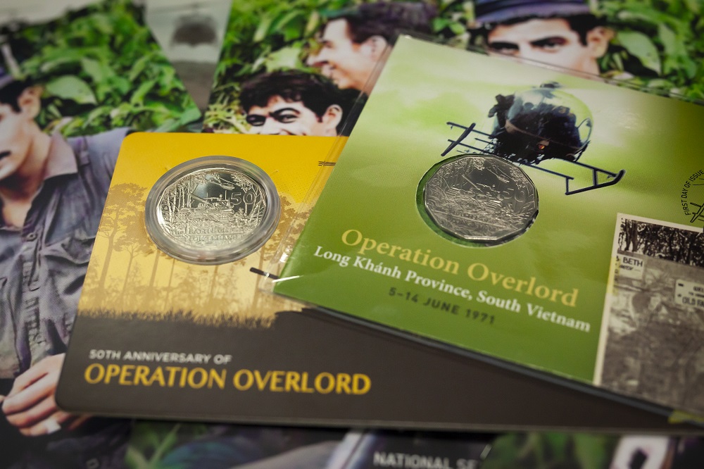 Coin packs showing a 50 cent coin with images of helicopters and tanks on the packaging