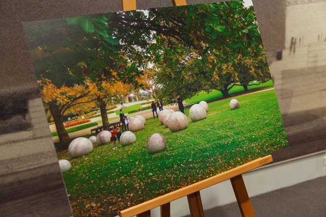 Photo of a photo on an easel showing a series of marble globules on grass