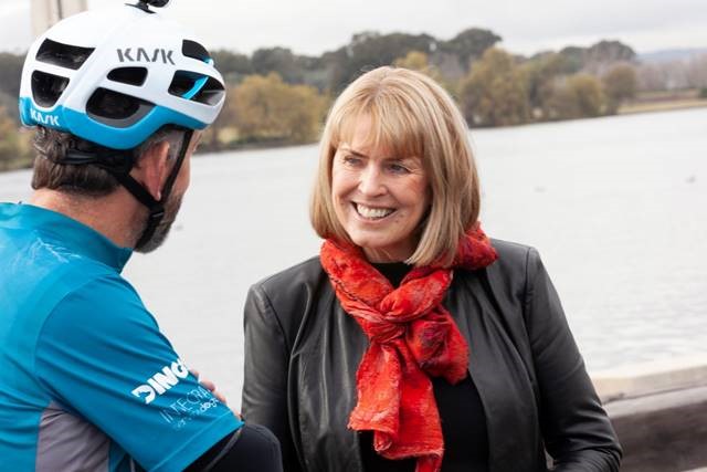 Smiling woman talking to cyclist with Lake in background