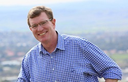 Smiling middle-aged man wearing check shirt with countryside in background