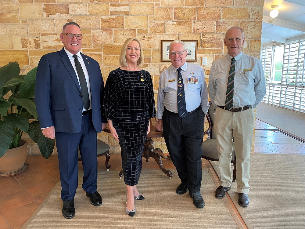 Three men and a woman posing for camera in front of a sandstone interior wall