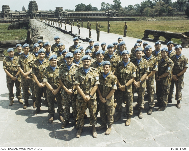 Soldiers wearing blue caps standing in formation in front of temple complex