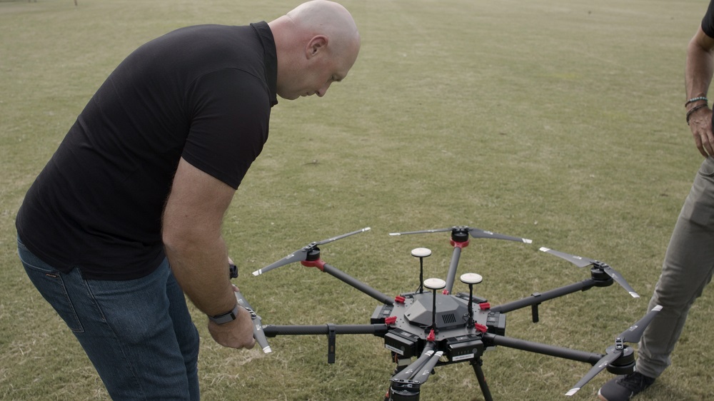 Man working on drone on expanse of grass