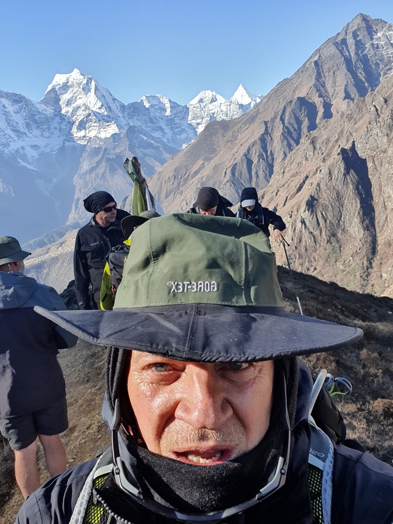 Man in cold weather gear with mountains and other hikers in background