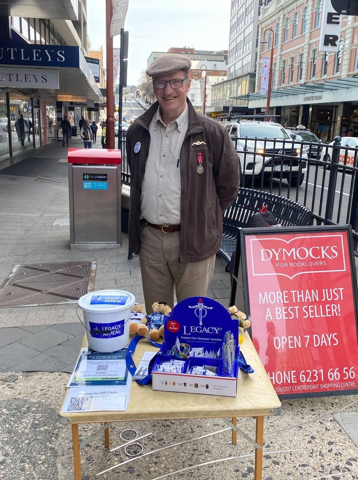 Older gentleman smiling at camera with Legacy collection paraphernalia