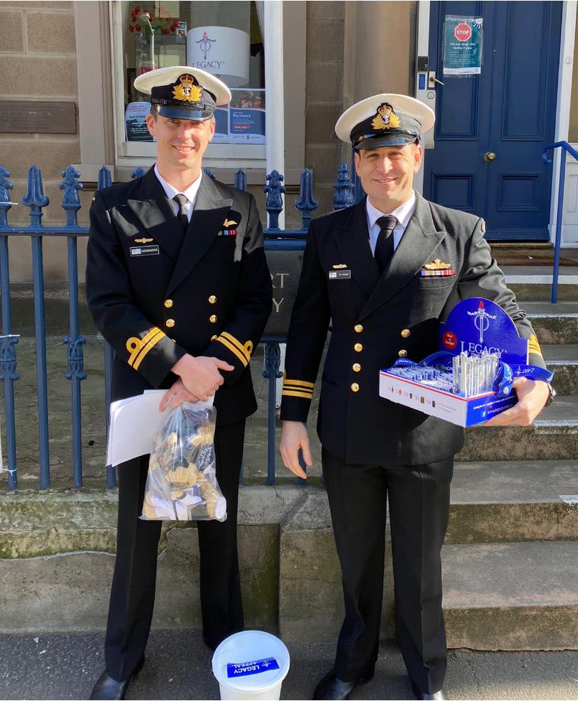 Two Navy officers smiling at camera with Legacy collection paraphernalia