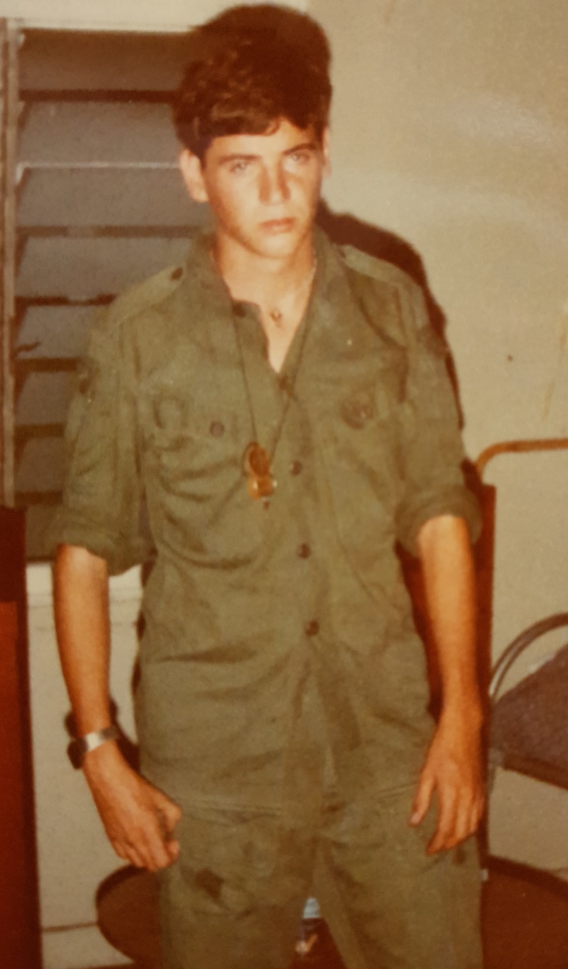 Very young man in Army uniform next to bunk bed