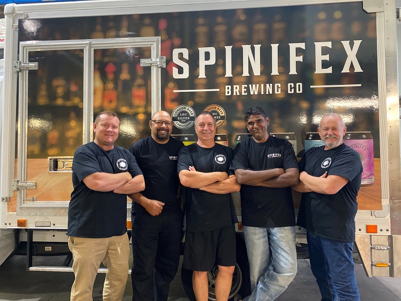 Five smiling men posing in front of truck with Spinifex Brewing Co emblazoned on side