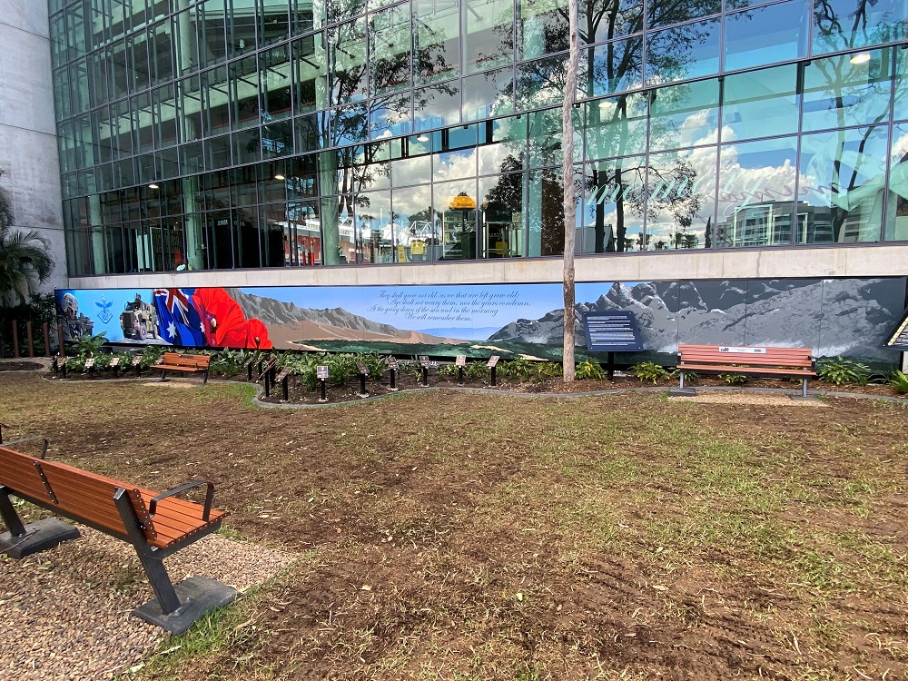 A remembrance garden under construction with a modern office block behind it