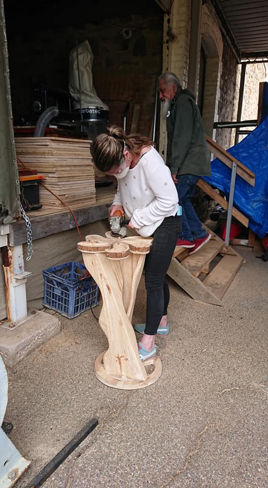 Woman works on timber structure inside large shed