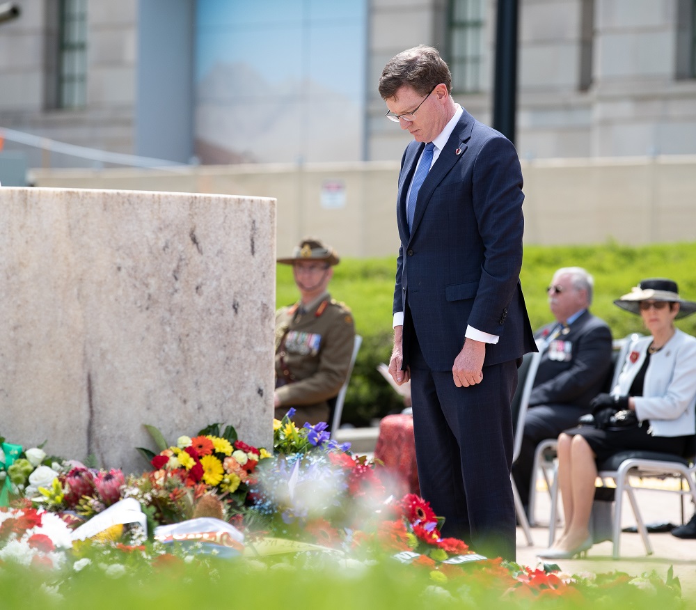 Man in suit bowing before stone memorial