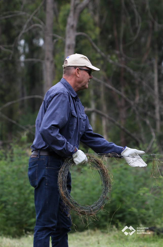 Middle aged man unreeling barbed wire