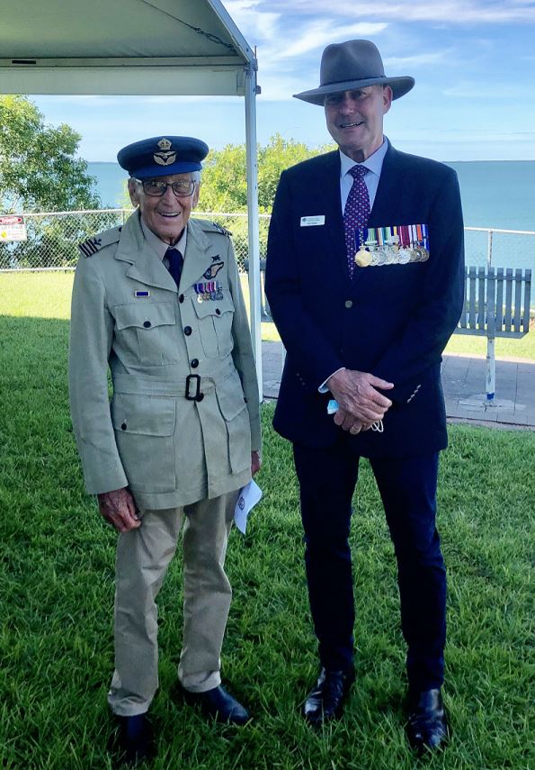 A middle-aged man wearing medals stands next to an elderly man in RAAF uniform