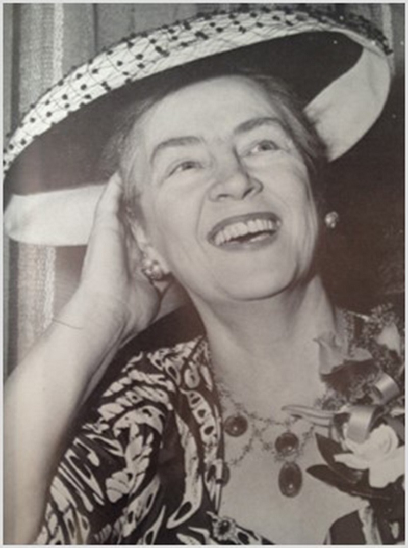 Black and white photo of middle-aged woman laughing, wearing a hat