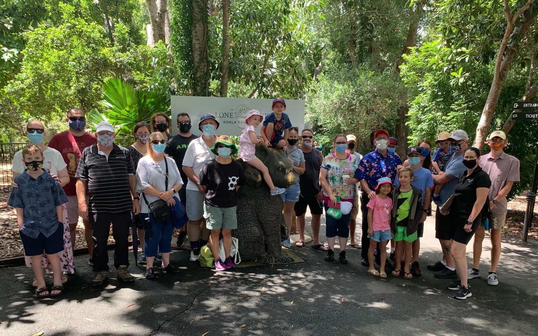 Group of 20 or so people of various ages pose for photo in bush setting