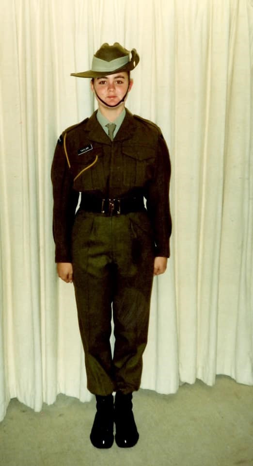 A young woman standing in front of curtains in full dress army uniform