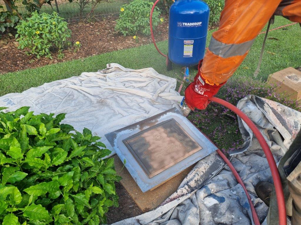 A bronze plaque being sand-blasted