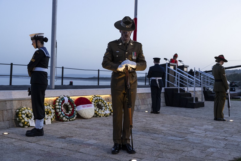 Two sailors and two soldiers stand with guns pointing down