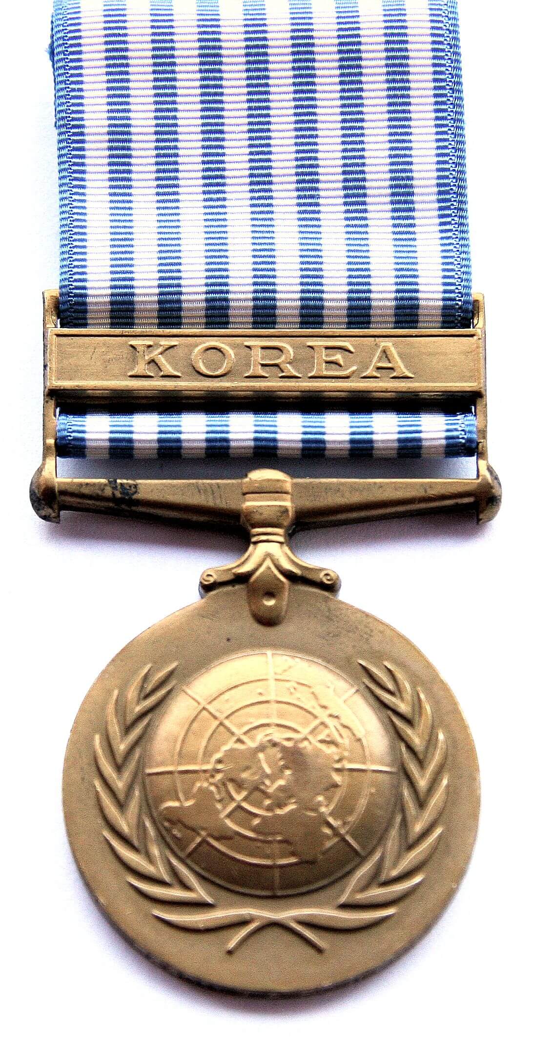 Studio shot of medal with Korea marked on it, and blue and white striped ribbon