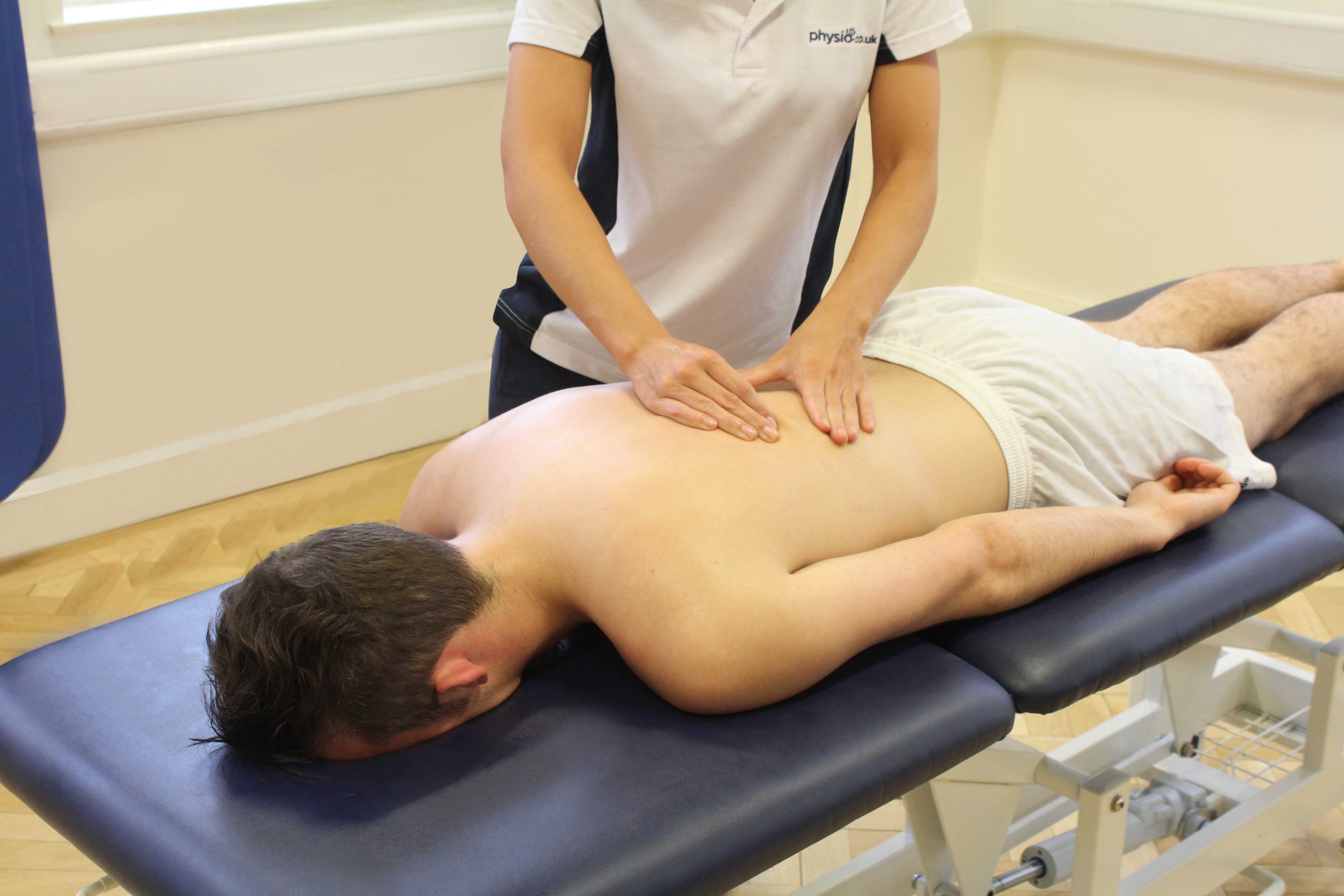 This picture shows a patient laying down on a massage table receiving treatment by a specialist.