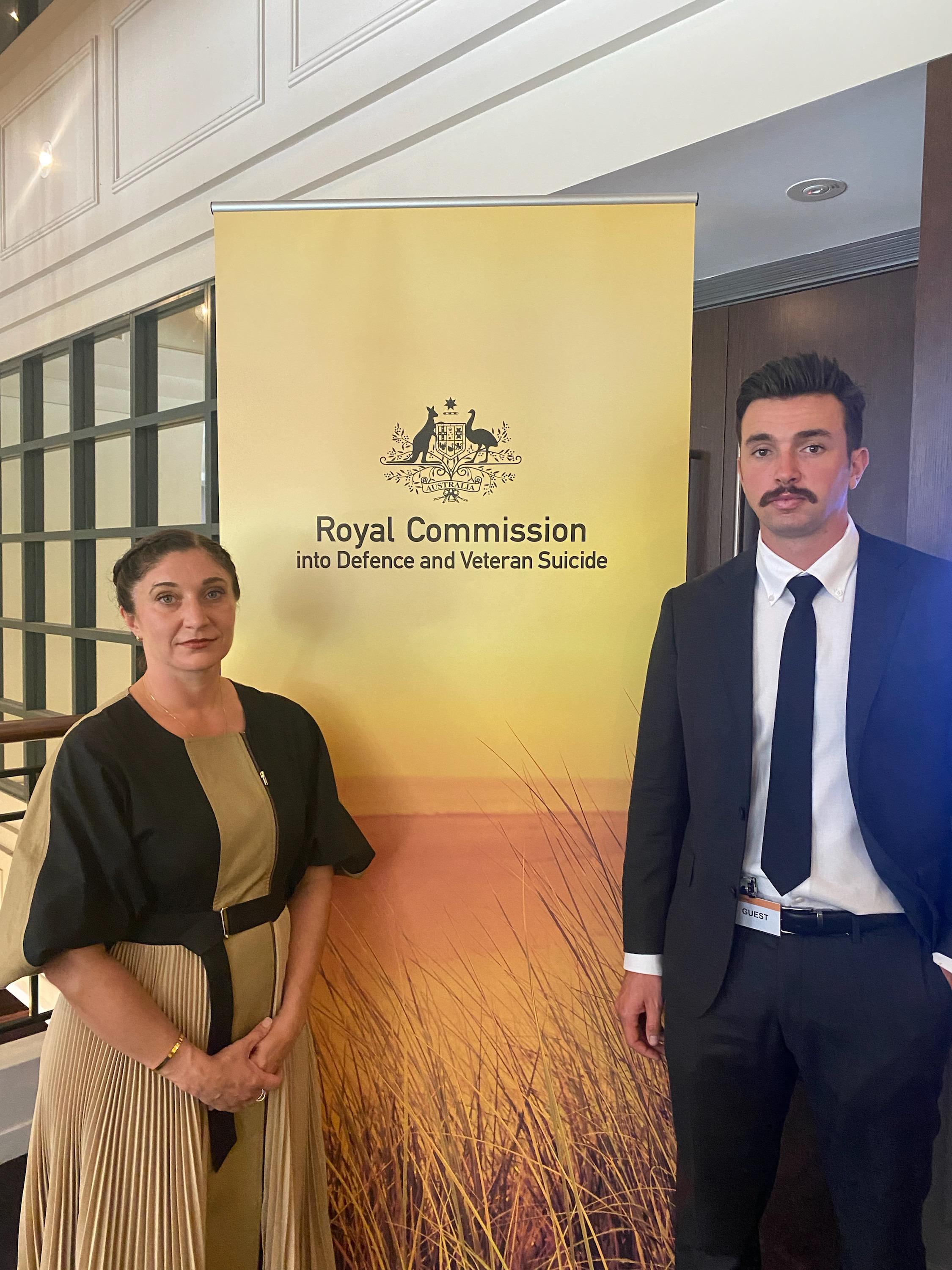 Woman and young man stand next to banner saying Royal Commission into Defence and Veteran Suicide