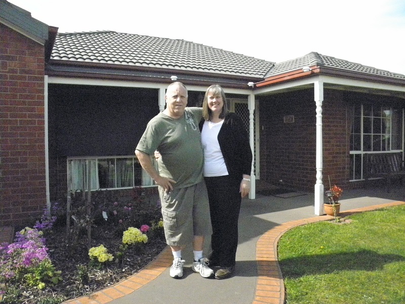 Middle-aged couple standing in front of a house