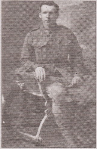 Young man in First World War uniform sitting on chair in photographer's studio