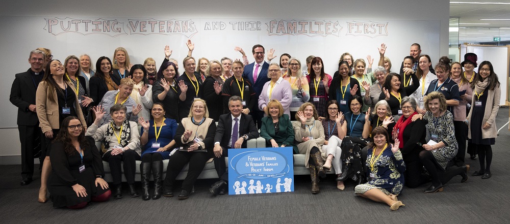 Group of about 40 women  and three men posing for camera in office