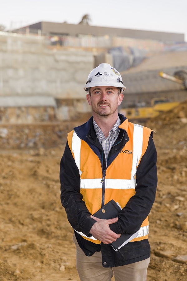 Young man in hard hat posing for camera on construction site