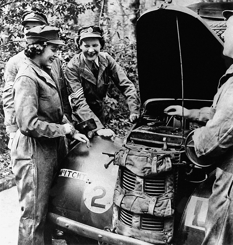 Two young women in overalls working on car