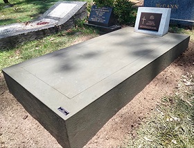 Image of a grave with a concrete infill and bronze plaque.