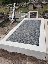 Image of a grave with a pebble infill and bronze plaque.