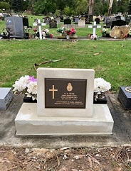 Image of grave monument with a bronze plaque set on a concrete base.