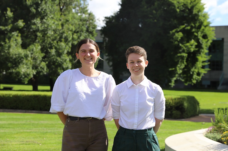 Two young women standing in pleasant grassy grounds