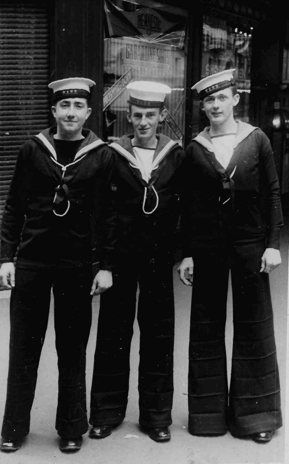 Black and white photo of three young sailors on city street