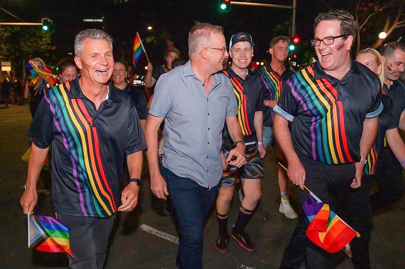 Three men at Mardi Gras, all smiling