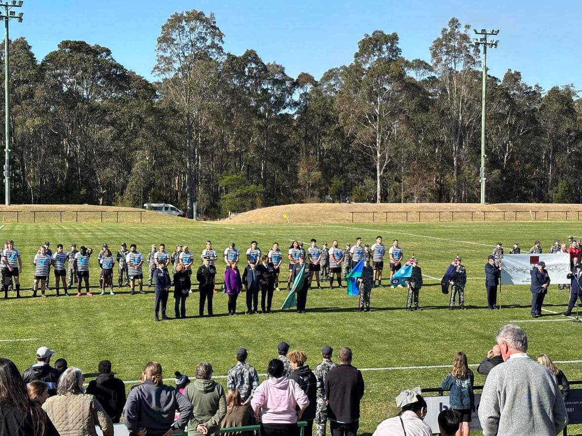 Various people standing on a football pitch, including a football team