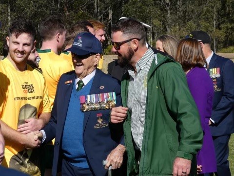 Elderly man smiling, shaking hands with football players