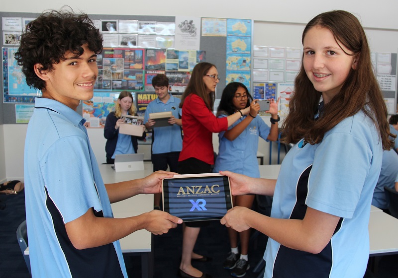 Two school kids hold ipad with Anzac XR on the screen