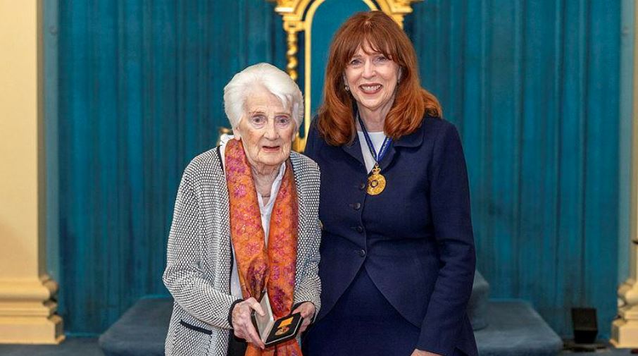 Middle-aged woman poses with elderly woman holding a medal