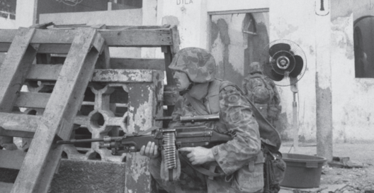 An Australian peacekeeper crouched behind pallets in Timor-Leste