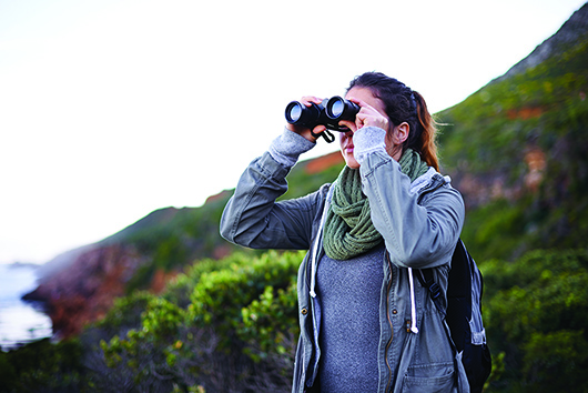 Young woman looking out through binoculars