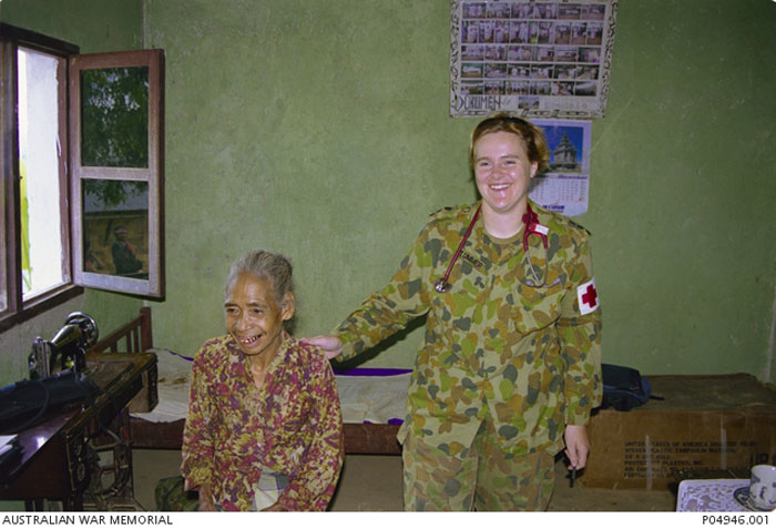 Two women smiling one is in camouflage uniform with a stethiscope while the other is a patient