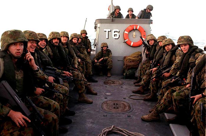 
A large group of fully uniformed and armed soldiers on a boat.