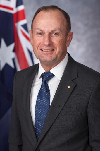 Portrait of middle aged man wearing a grey suit and a blue tie.