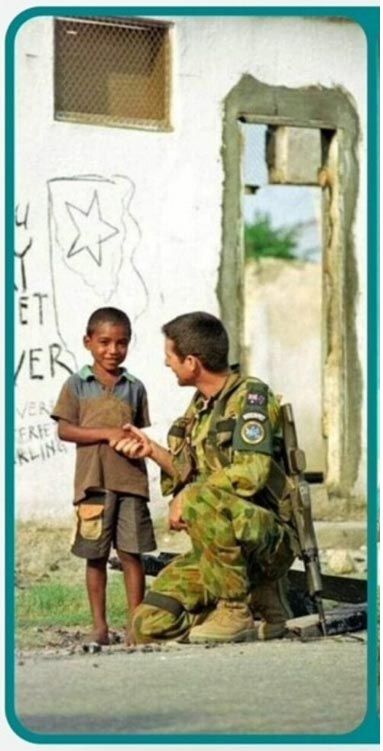 A young soldier shaking a hand with an East-Timorese child.