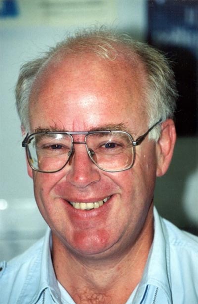 A photo showing a smiling face of a middle aged man wearing glasses.