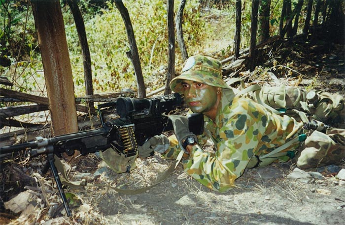 A young soldier shooting from a machine gun