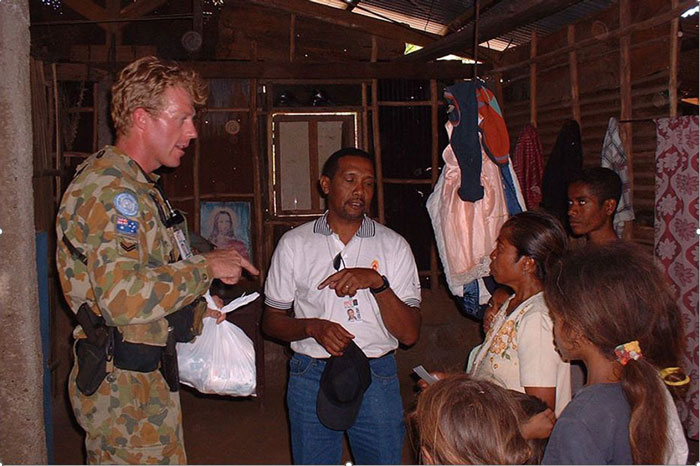 A man in green camouflage overalls meets a Timorese family