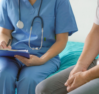 person wearing medical scrubs holding note pad while talking with a another person